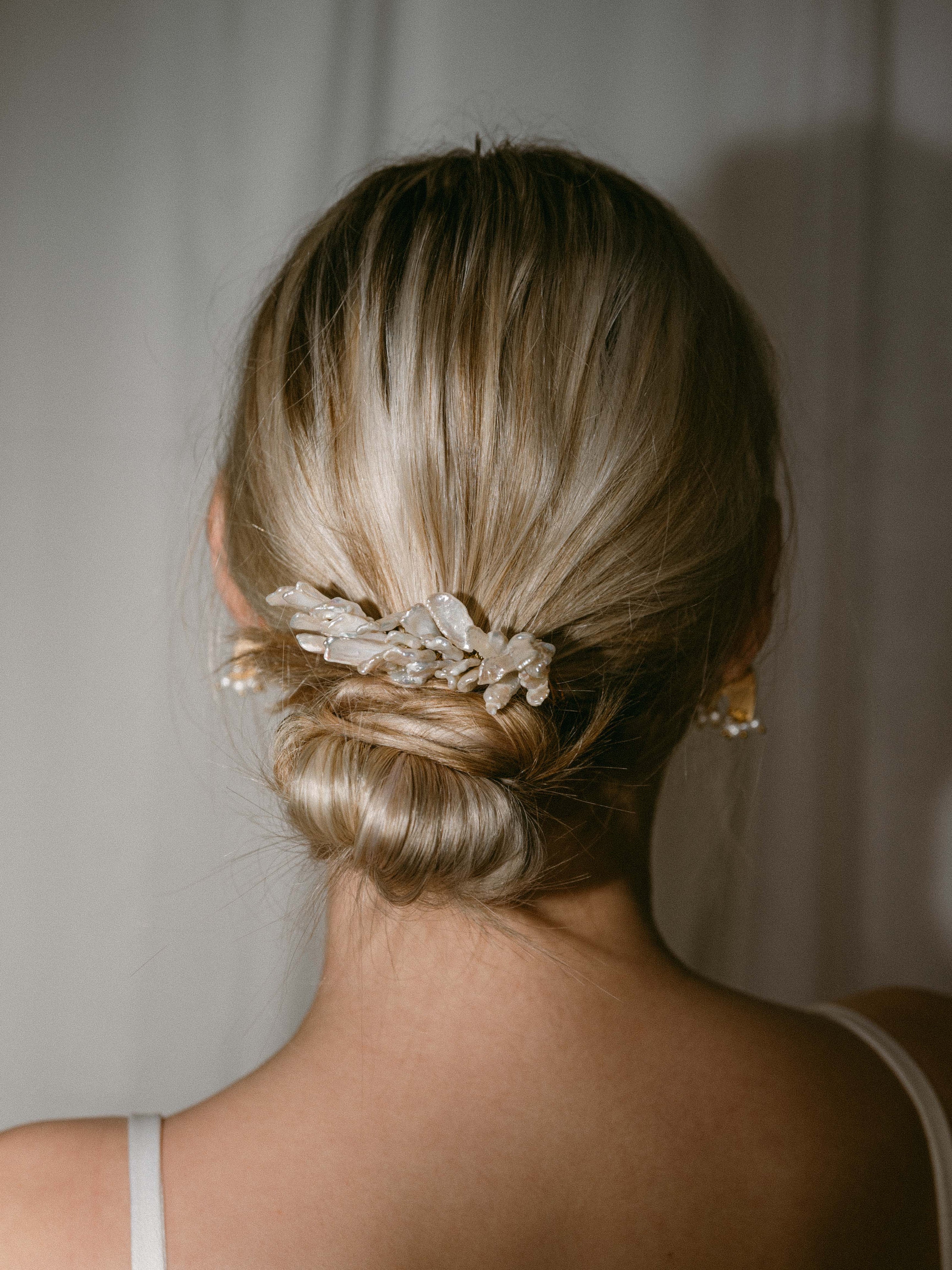 A back view of a bridal up do with a freshwater pearl hair accessory.